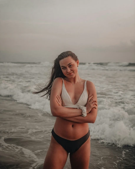 a woman in a bikini standing by the ocean
