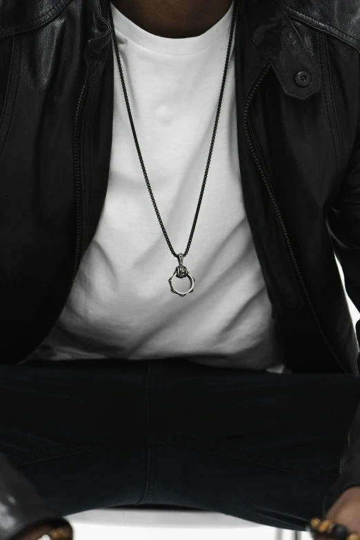 a young man in black and white wearing a necklace with a skull on it