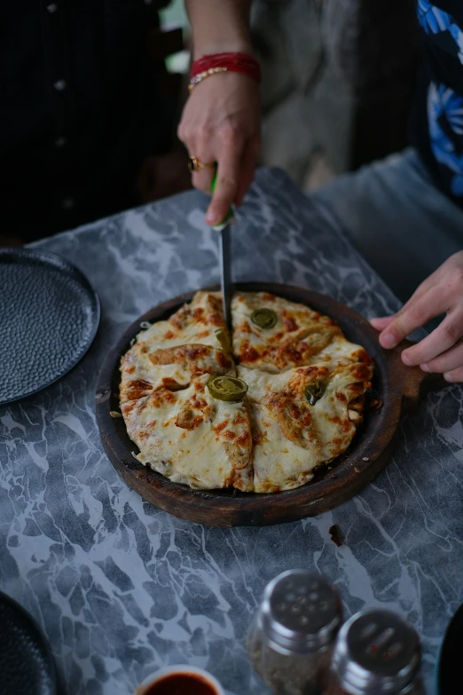 a person cuts a pizza with a knife on top of it