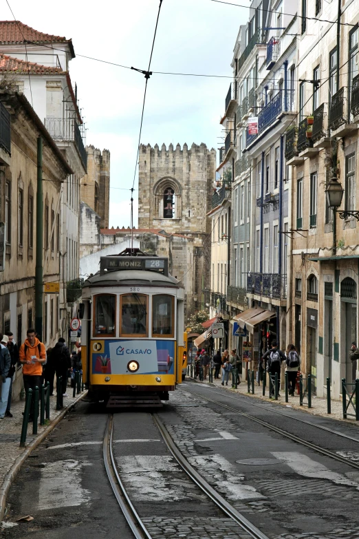 a yellow and blue trolley and people on street