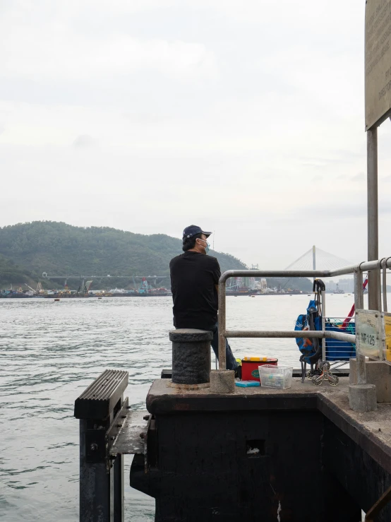 a man is fishing on the dock and sitting down