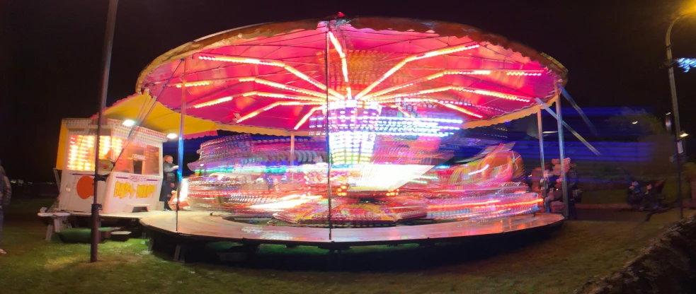 a ferris wheel ride at night time with lit up umbrellas