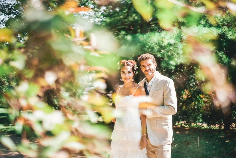 a newly married couple standing together in a field