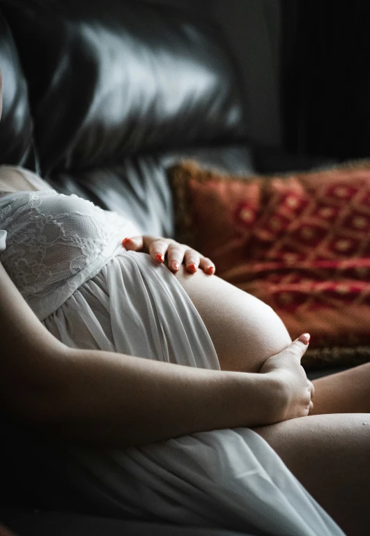 a pregnant woman lies on a bed in her diapers