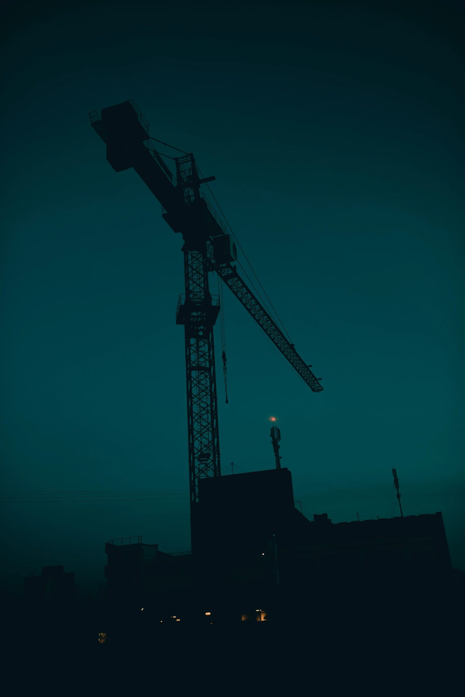 the silhouette of a construction crane against a blue sky