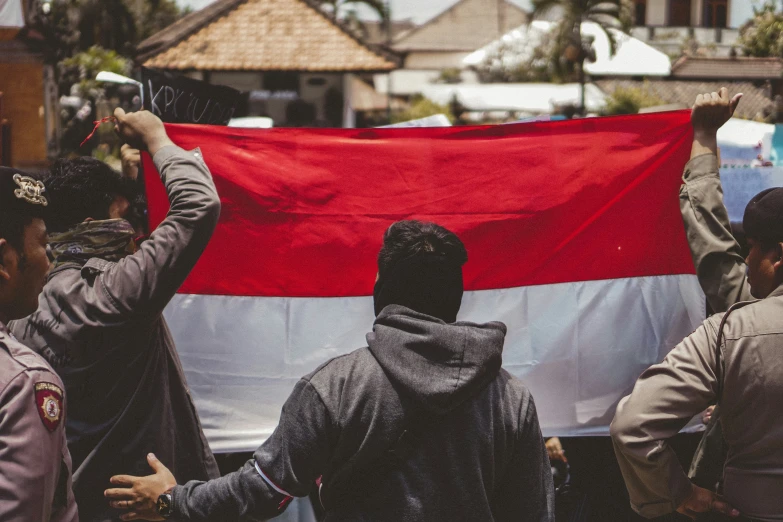 a group of people hold up a flag in the street