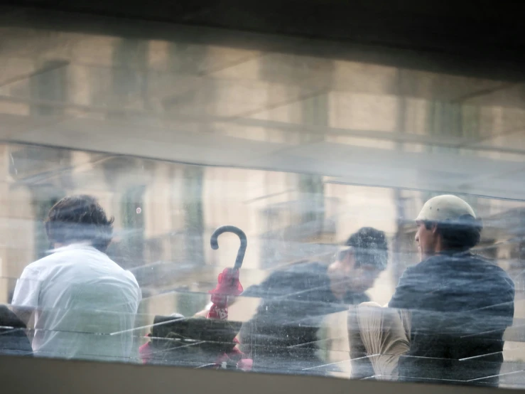 some people looking out a window at some umbrellas