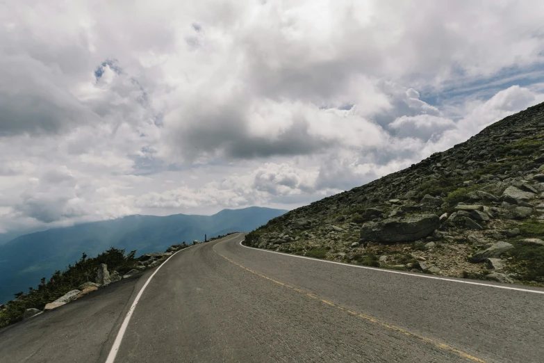 the car is driving down the road on the mountain