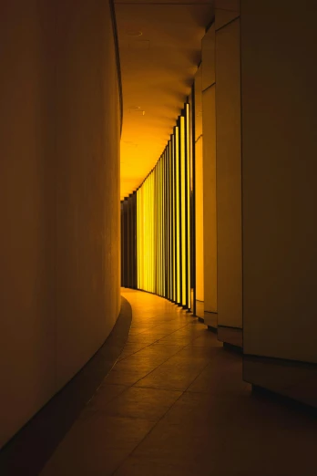 the long narrow corridor in an office building is illuminated by yellow lights