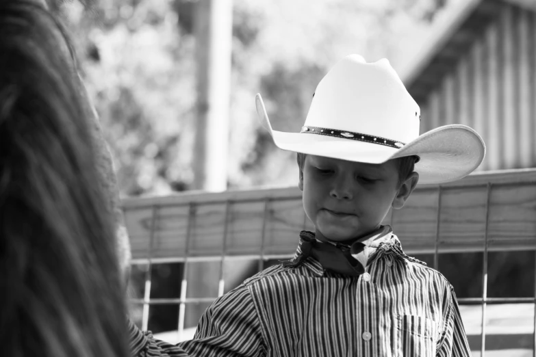 a little boy wearing a cowboy hat in the dirt