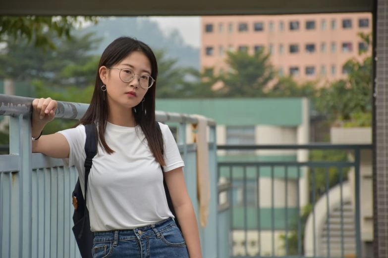 a woman leaning up against a railing looking at the camera