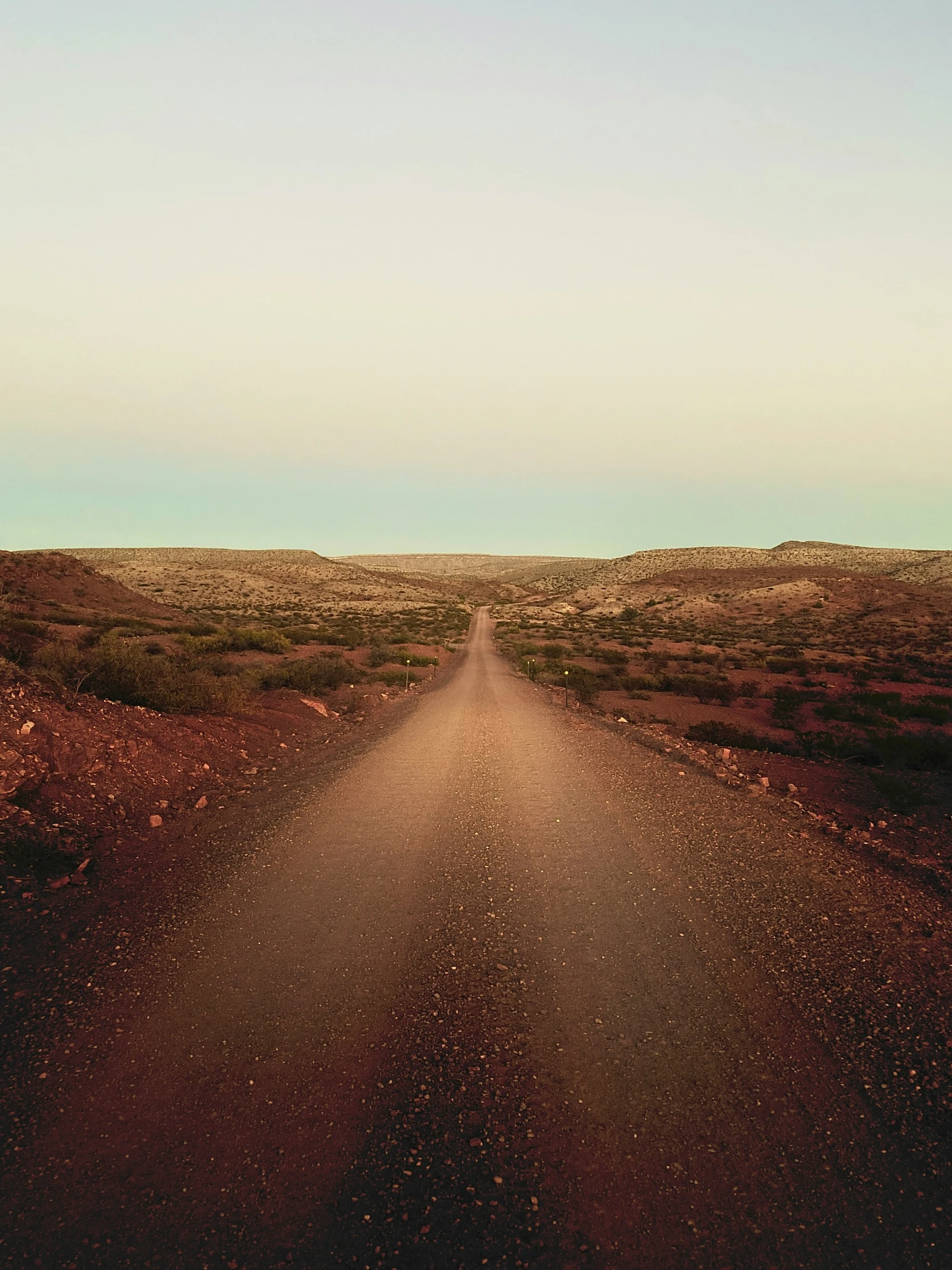 a dirt road leading to the sky near a desert landscape