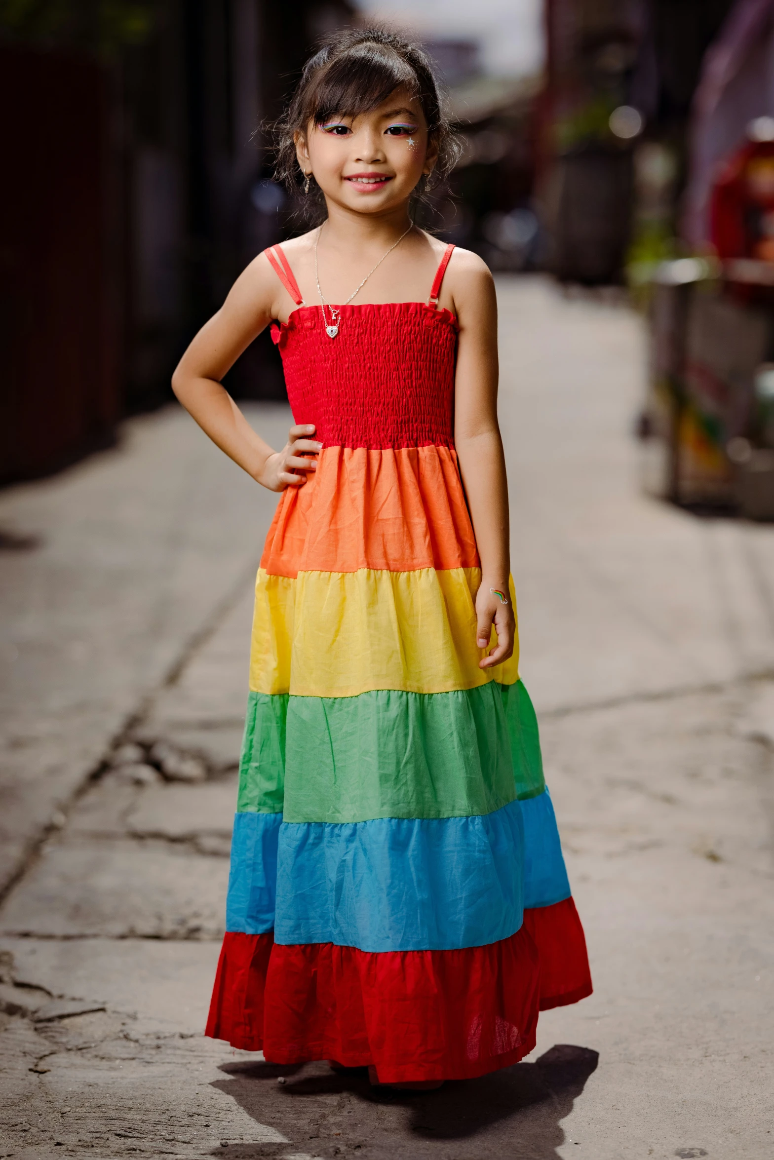 a little girl is dressed in a multi colored dress