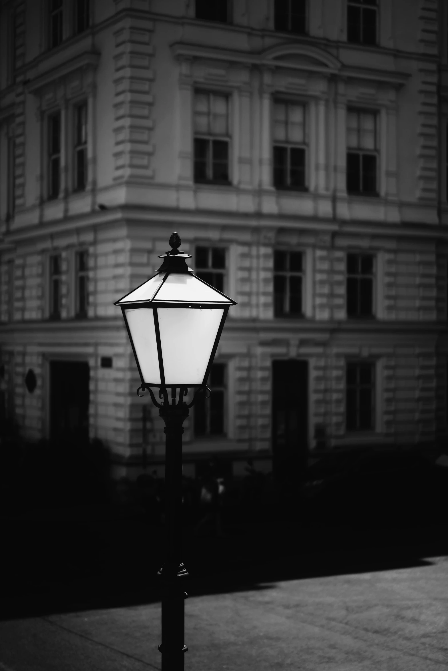 a lamp post on a dark sidewalk near a building