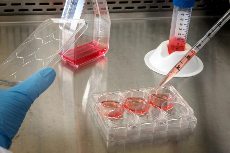 the scientist's hands are holding test tubes as they pour liquid into two small cups