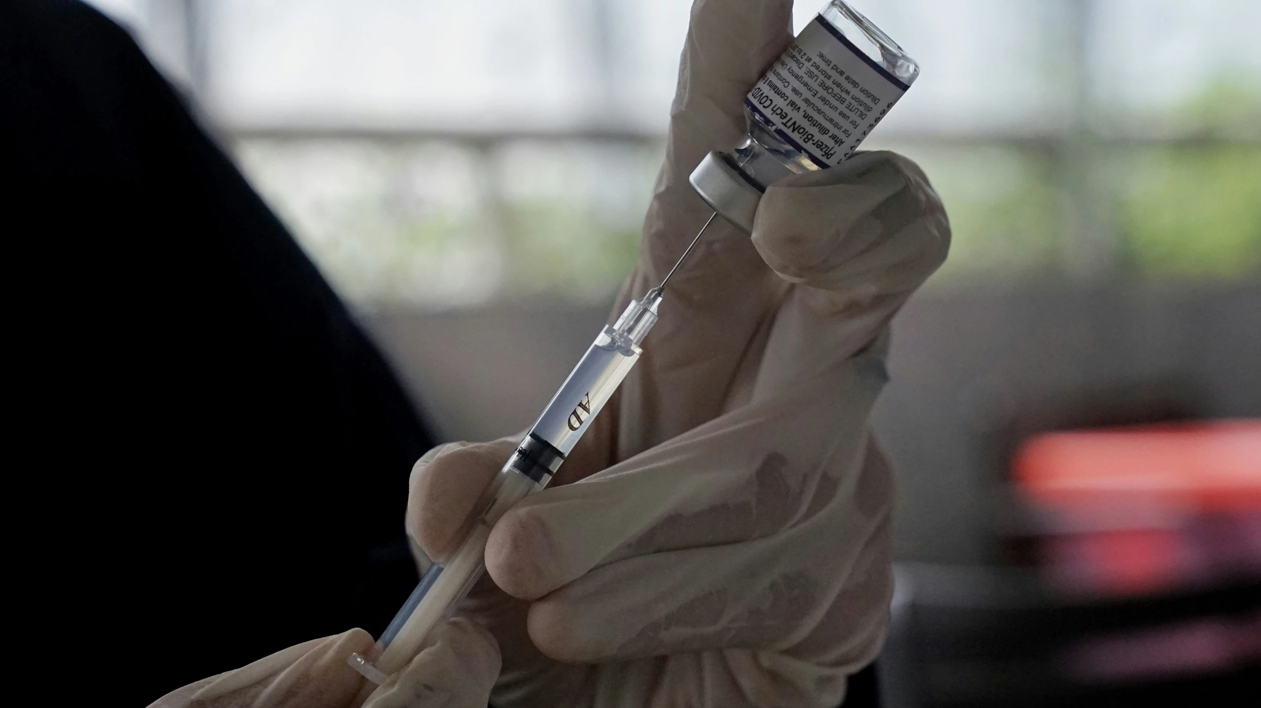 gloved hands holding a small cell phone with a silver band