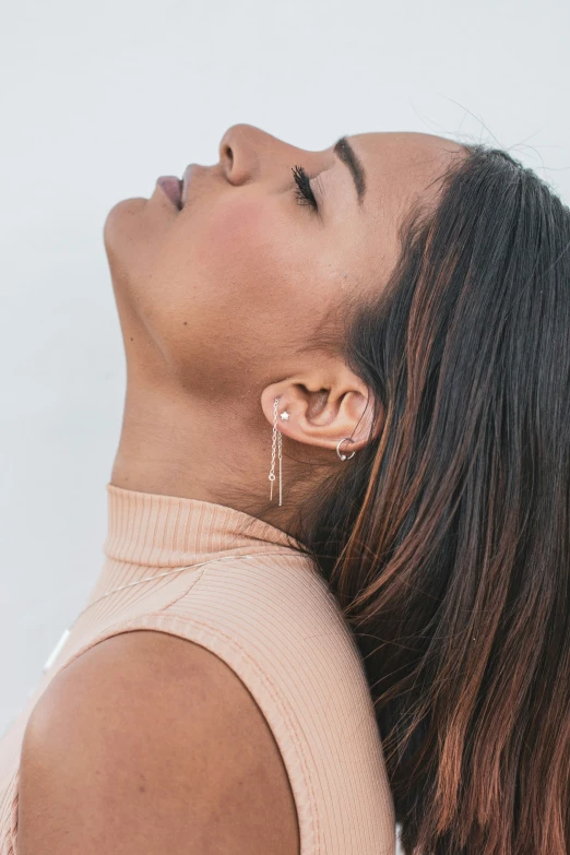 a young woman looking up at the sky and wearing some earrings