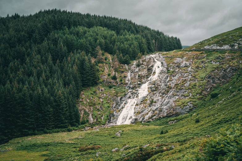 the hillside has a narrow waterfall on it