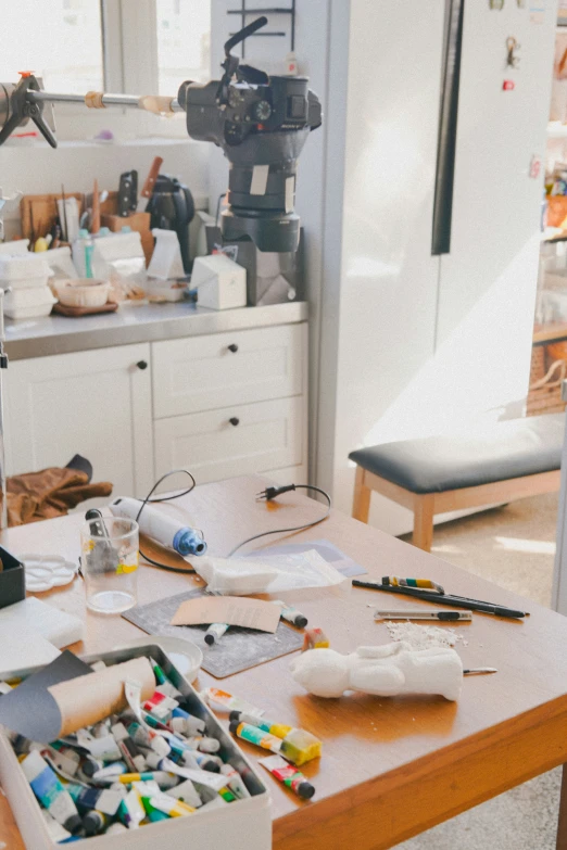 messy table with a camera, various items, and craft supplies