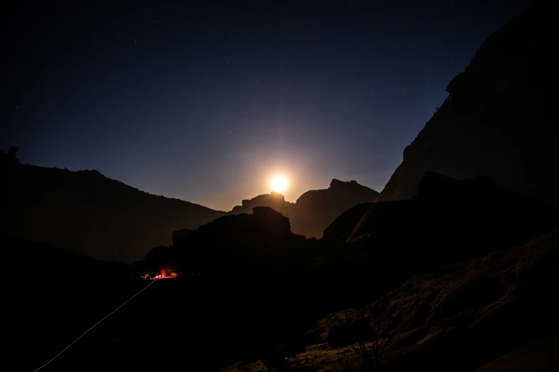 the sun rising through the mountains with a mountain scene in view