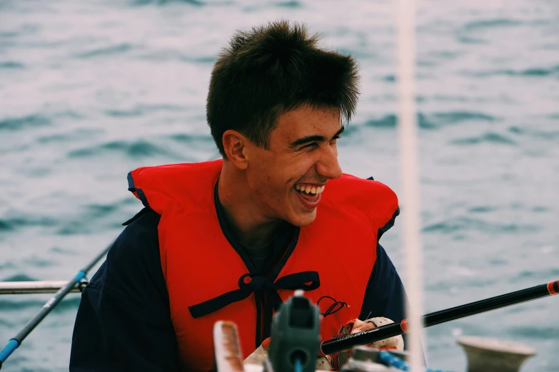 the smiling man is wearing an orange life jacket