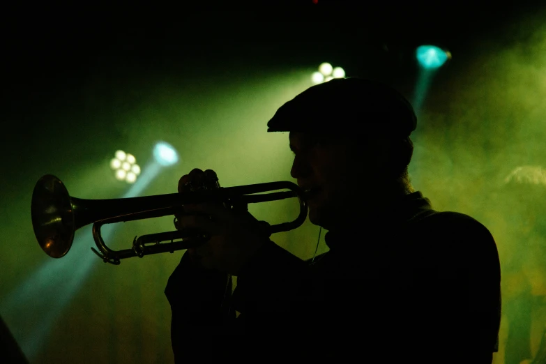 the silhouette of a trumpet player is seen in front of the crowd