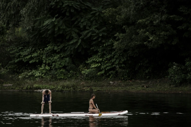 two people stand on a boat on a body of water