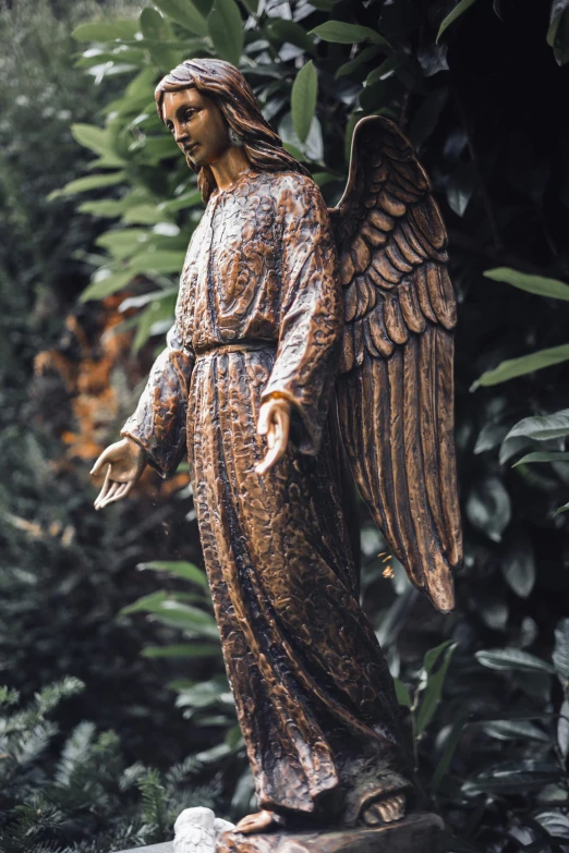 a statue of an angel standing in the middle of some bushes