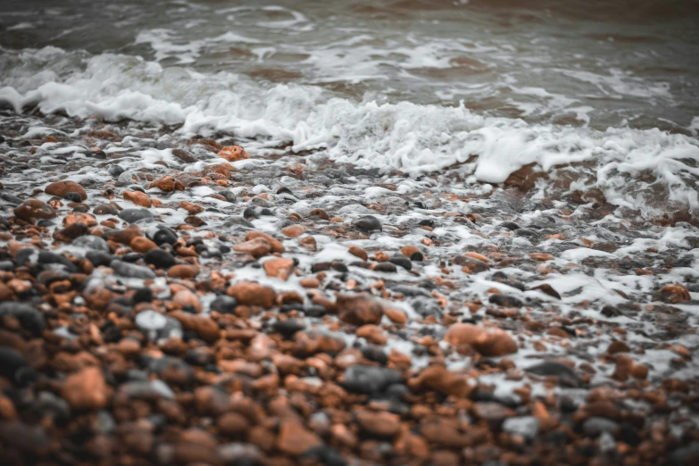 water crashing on shore with rocks and rocks in foreground