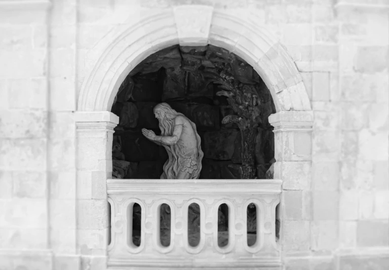 a statue is on a stone window ledge