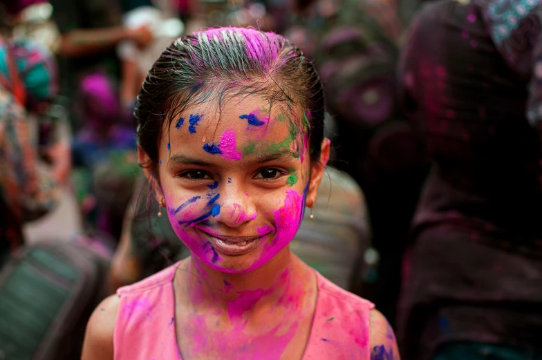 a small child smiles while she has smeared all her body with color