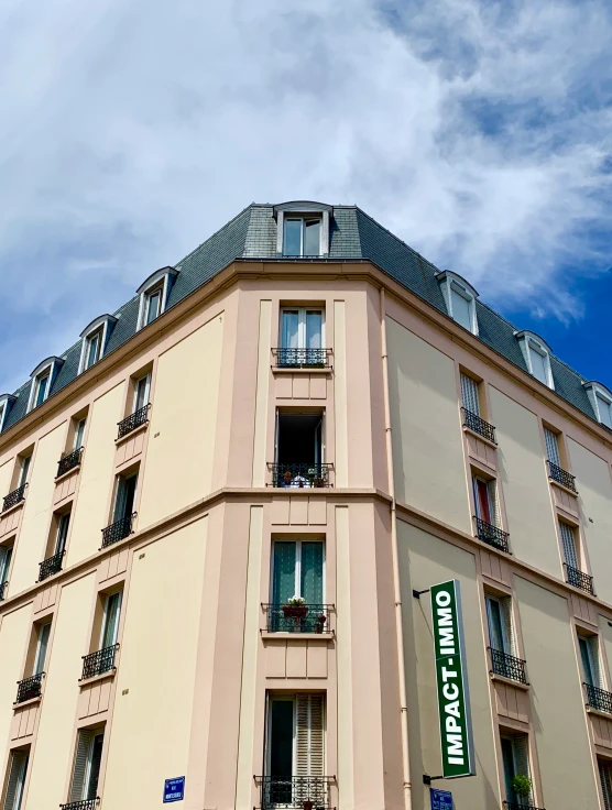 the corner of an apartment building under a cloudy blue sky