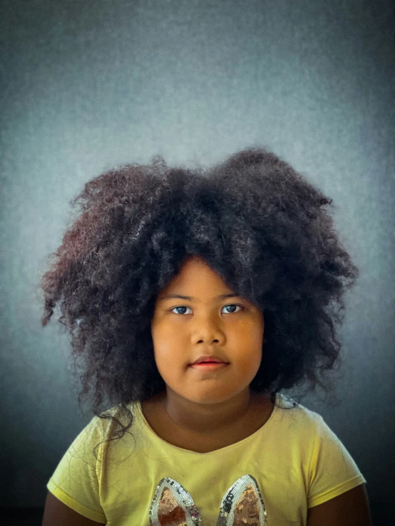 a  wearing a yellow shirt with an afro on her head