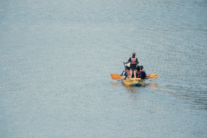 three men are riding in a kayak in the water
