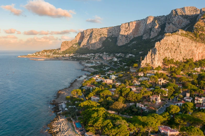 a bird - eye view of the shoreline and rocky mountains behind the village