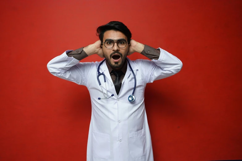 a man in a white coat covers his ears with his hands