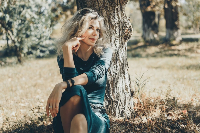 woman sitting in front of a tree leaning against it