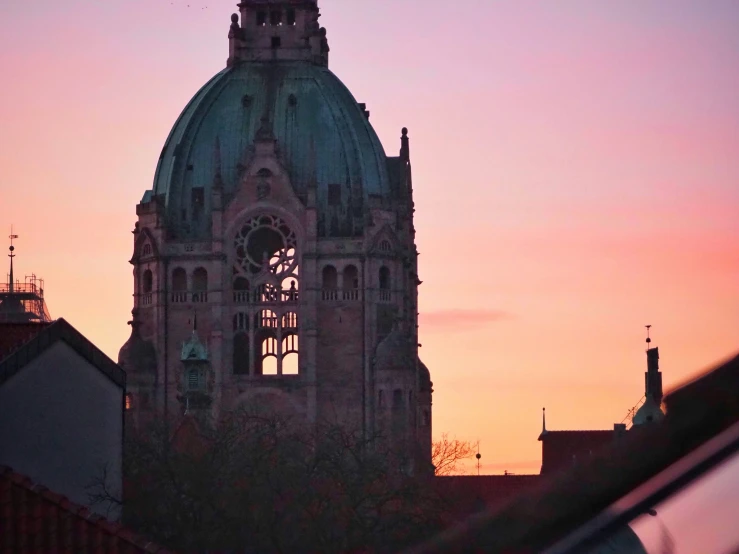 a silhouette of a building with a clock at sunset