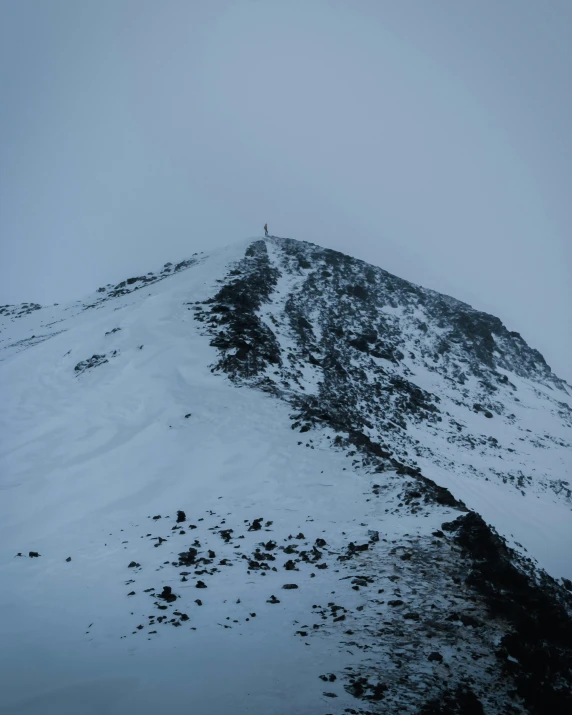 a mountain with snow on the top and a person on a snowboard on the side of it