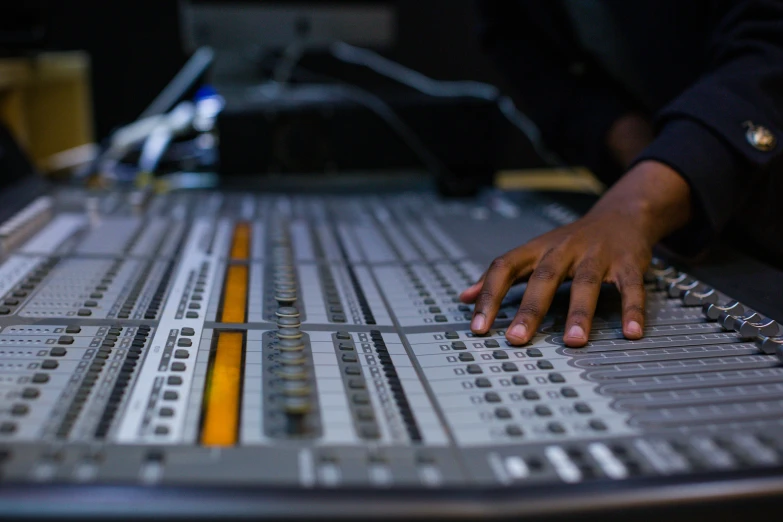 a man's hand resting on top of a sound equipment console