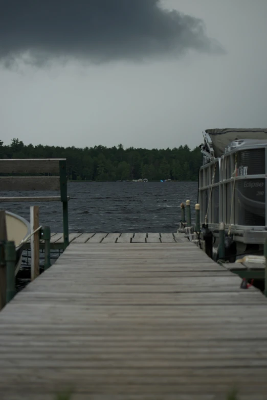 a pier with several boats and cloudy skies