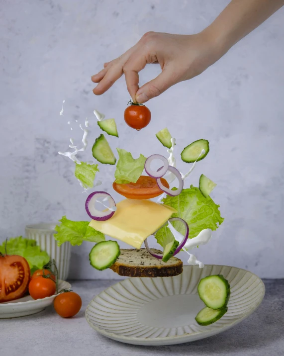 a salad being shredded into pieces with a hand touching the tomato on top