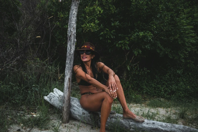 a woman sitting on a tree stump in a bikini