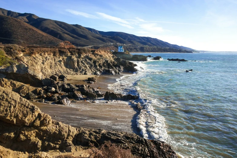 a view of the beach and mountains by the water