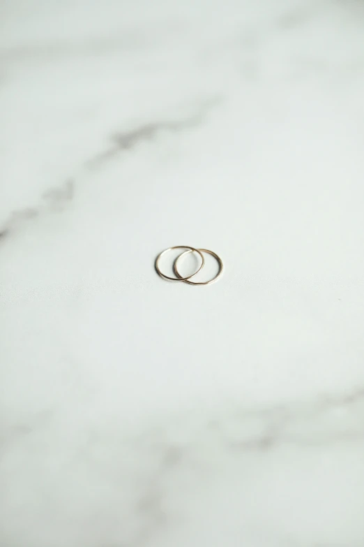 two wedding rings are displayed on a marble surface