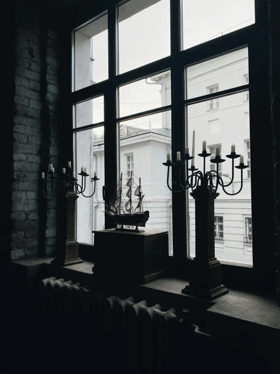 three candles stand on a window ledge near large windows