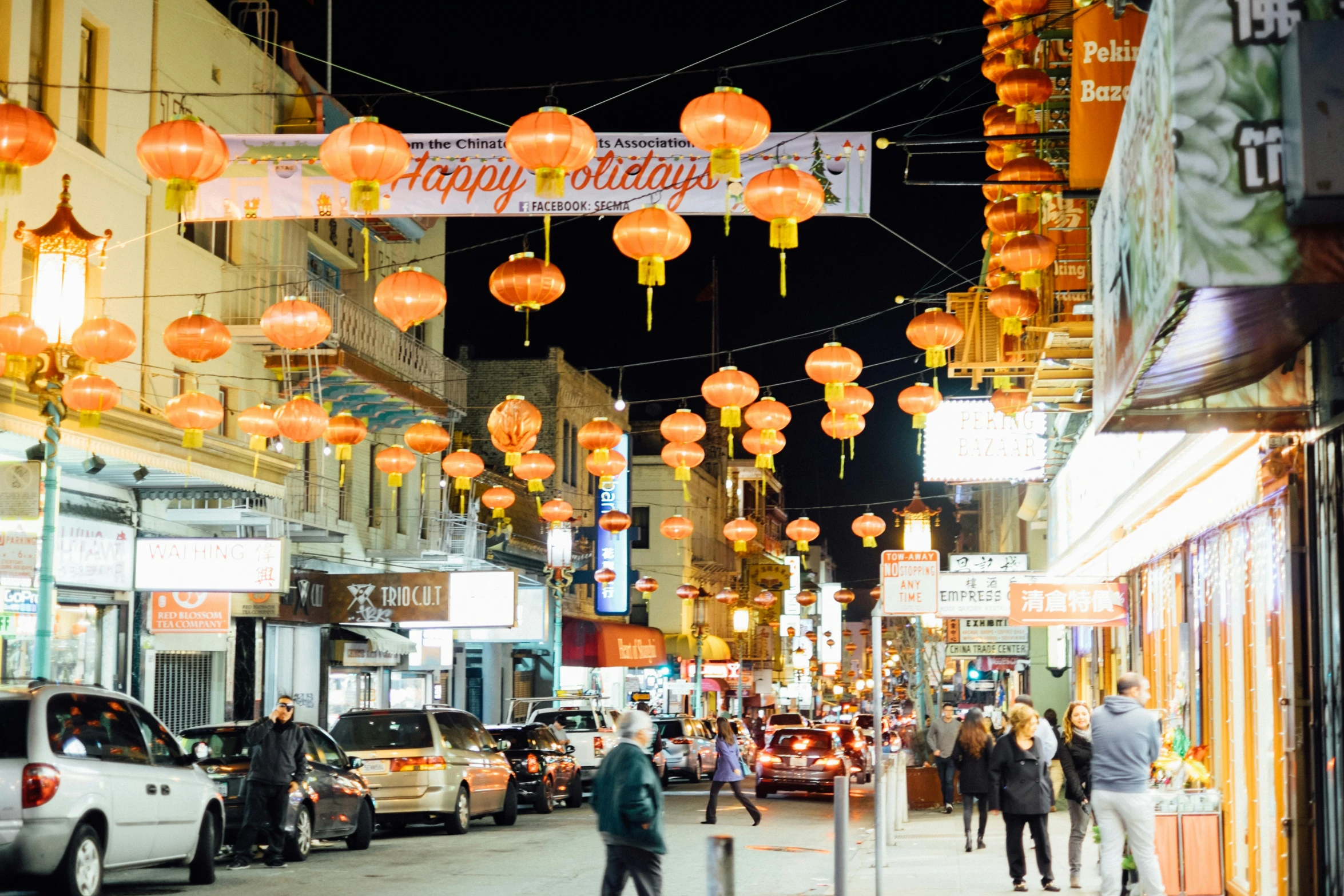 several people walk through an alley in a shopping district at night