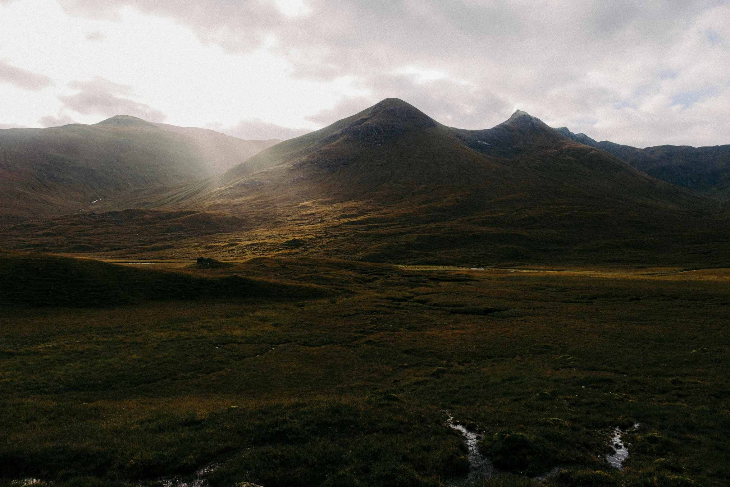 the mountains are covered with green grass and water