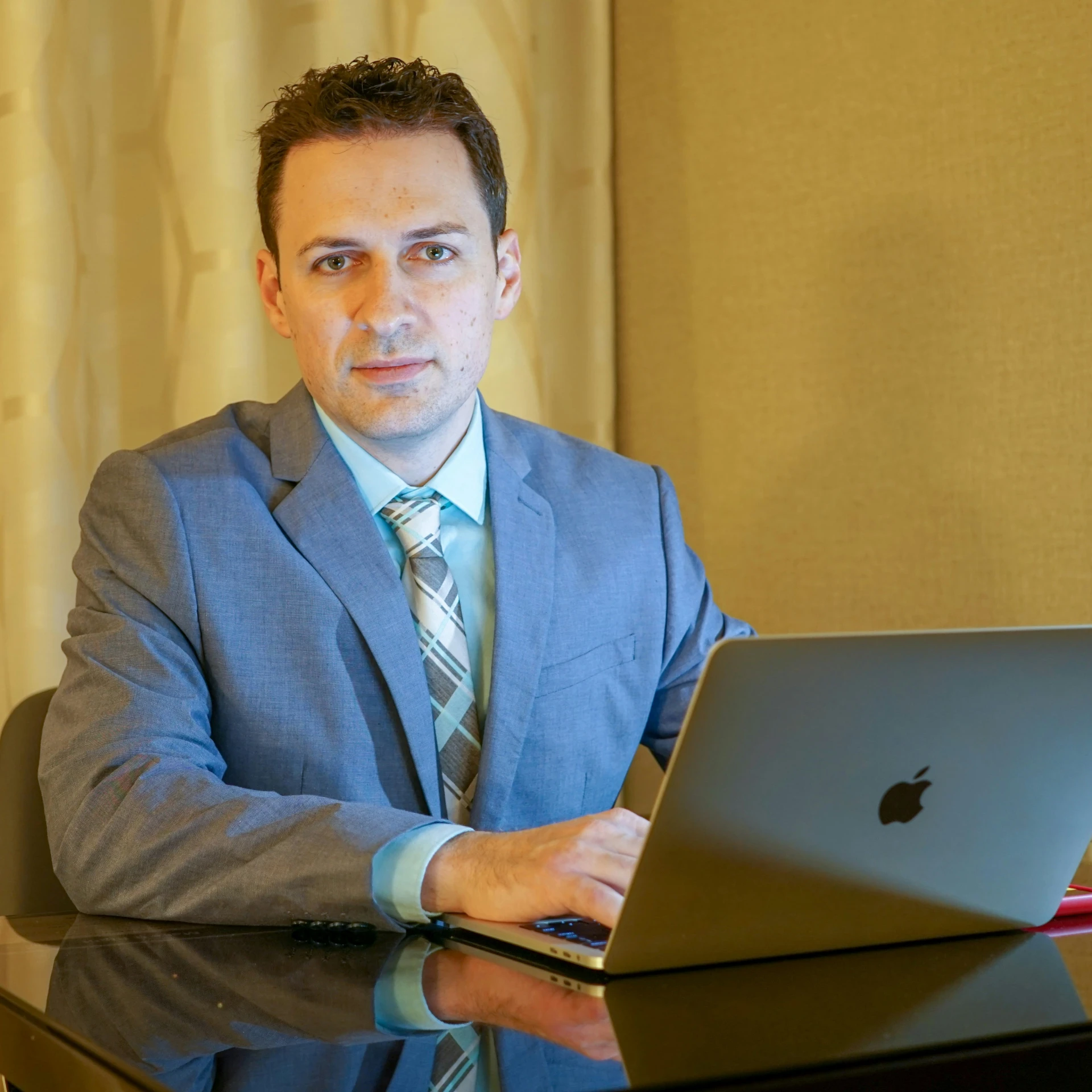 a man in a suit sitting in front of his laptop