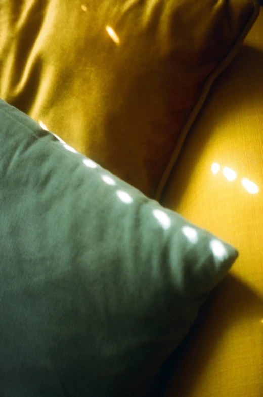 three different types of pillows are set on a yellow sofa